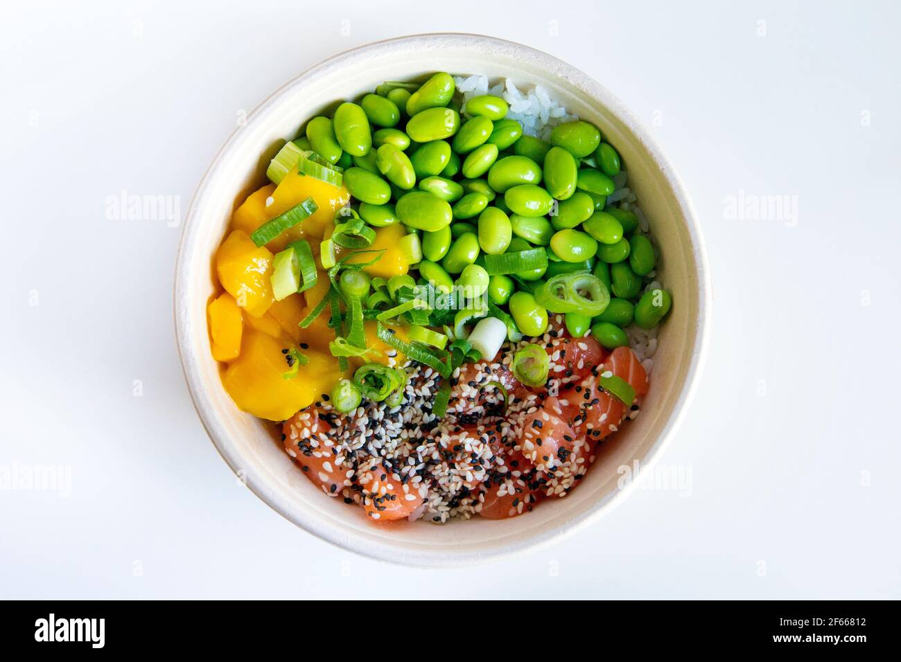 Un bol à poke avec de l'edamame, du saumon, de la mangue, recouvert d'oignons de printemps et de sésame sur un lit de riz Banque D'Images