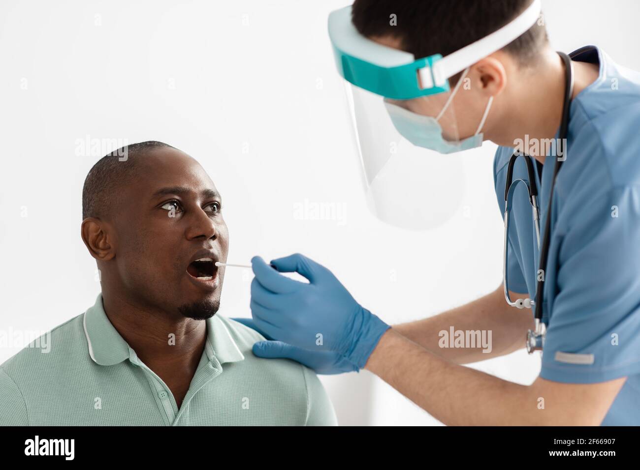 Médecin prenant un écouvillon de bouche de la personne à tester pour la possibilité infection à coronavirus Banque D'Images