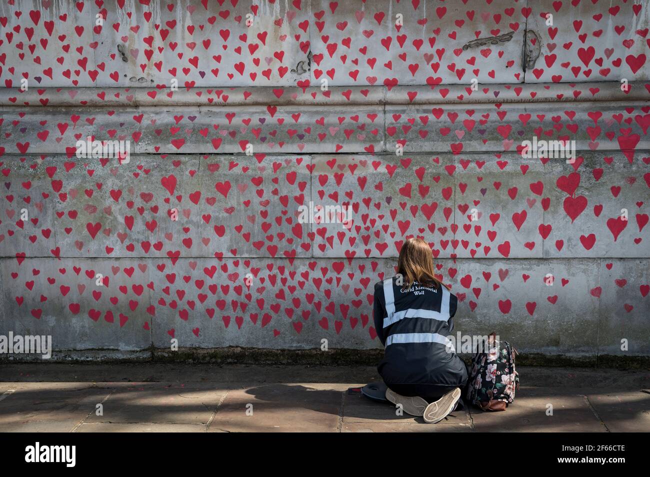 Londres, Royaume-Uni. 30 mars 2021. Un volontaire tire les coeurs sur un mur à Lambeth près de la Tamise, chaque coeur représentant quelqu'un qui est décédé pendant la pandémie de coronavirus au Royaume-Uni. Appelé le mur commémoratif national Covid, il a été créé par les familles bereaved Covid-19 pour la justice et s'étendra sur un demi-mile au moment où il sera terminé. Crédit : Stephen Chung/Alay Live News Banque D'Images