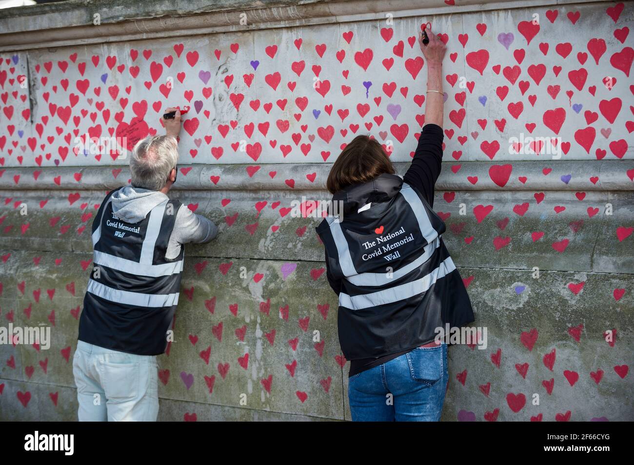 Londres, Royaume-Uni. 30 mars 2021. Les volontaires tirent les coeurs sur un mur à Lambeth, près de la Tamise, chaque coeur représentant quelqu'un qui est décédé pendant la pandémie de coronavirus au Royaume-Uni. Appelé le mur commémoratif national Covid, il a été créé par les familles bereaved Covid-19 pour la justice et s'étendra sur un demi-mile au moment où il sera terminé. Crédit : Stephen Chung/Alay Live News Banque D'Images