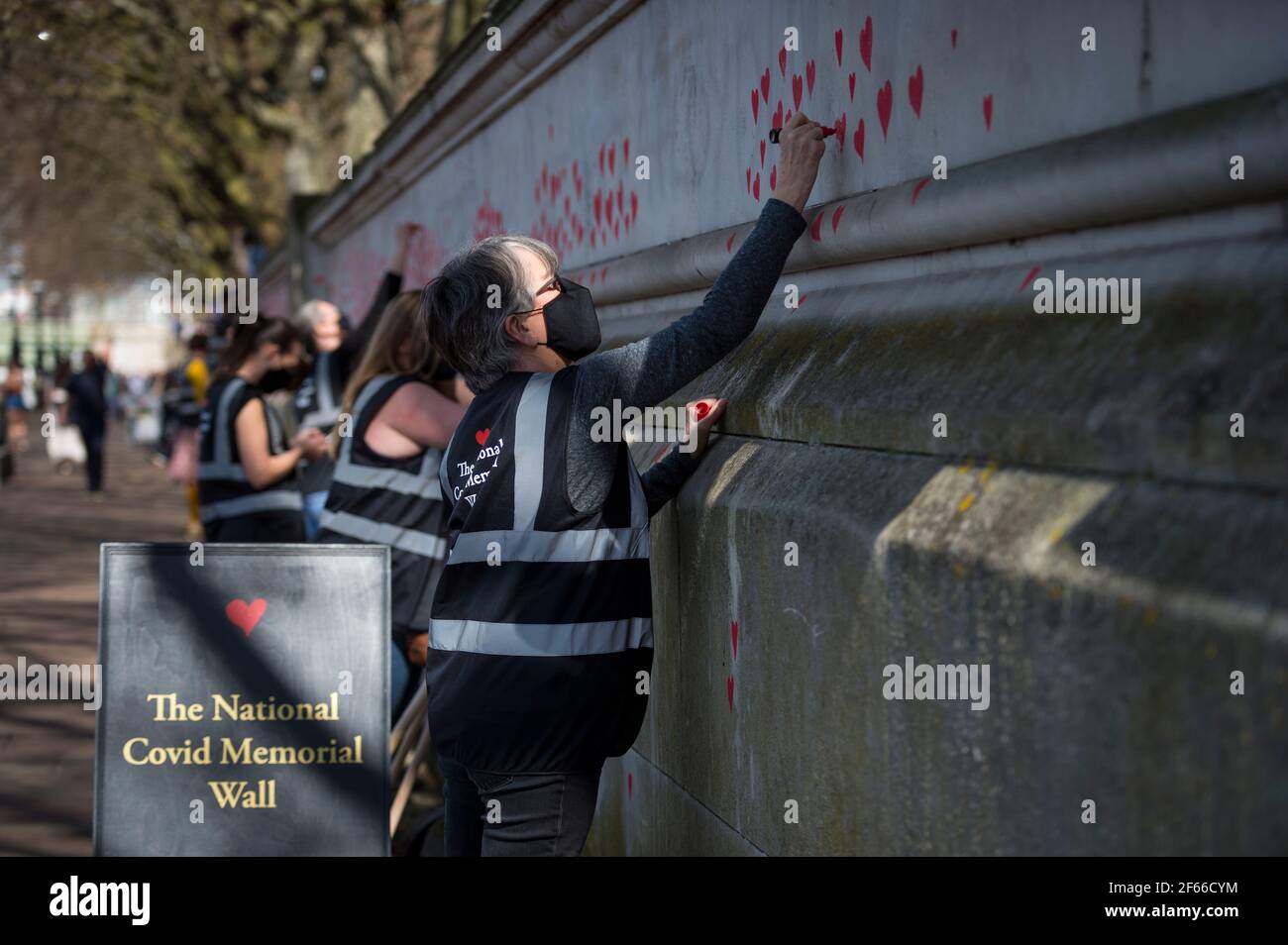 Londres, Royaume-Uni. 30 mars 2021. Un volontaire tire les coeurs sur un mur à Lambeth près de la Tamise, chaque coeur représentant quelqu'un qui est décédé pendant la pandémie de coronavirus au Royaume-Uni. Appelé le mur commémoratif national Covid, il a été créé par les familles bereaved Covid-19 pour la justice et s'étendra sur un demi-mile au moment où il sera terminé. Crédit : Stephen Chung/Alay Live News Banque D'Images