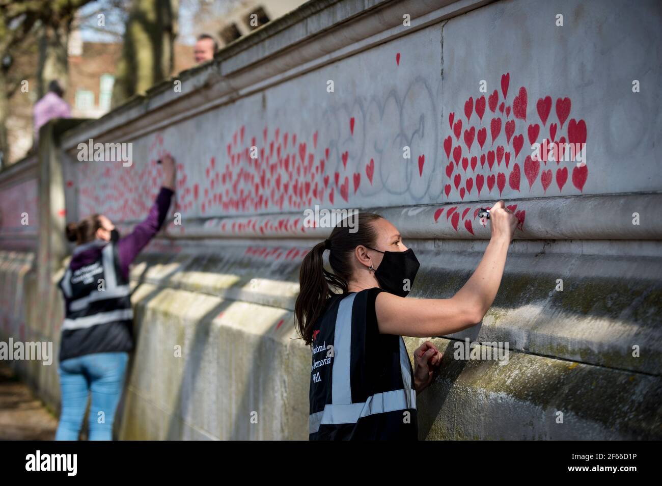 Londres, Royaume-Uni. 30 mars 2021. Les volontaires tirent les coeurs sur un mur à Lambeth, près de la Tamise, chaque coeur représentant quelqu'un qui est décédé pendant la pandémie de coronavirus au Royaume-Uni. Appelé le mur commémoratif national Covid, il a été créé par les familles bereaved Covid-19 pour la justice et s'étendra sur un demi-mile au moment où il sera terminé. Crédit : Stephen Chung/Alay Live News Banque D'Images