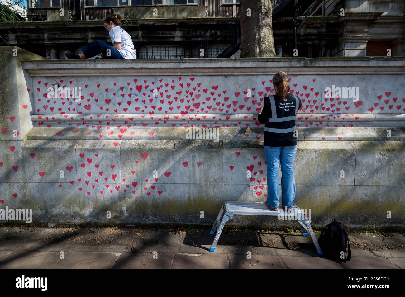 Londres, Royaume-Uni. 30 mars 2021. Un volontaire tire les coeurs sur un mur à Lambeth près de la Tamise, chaque coeur représentant quelqu'un qui est décédé pendant la pandémie de coronavirus au Royaume-Uni. Appelé le mur commémoratif national Covid, il a été créé par les familles bereaved Covid-19 pour la justice et s'étendra sur un demi-mile au moment où il sera terminé. Crédit : Stephen Chung/Alay Live News Banque D'Images