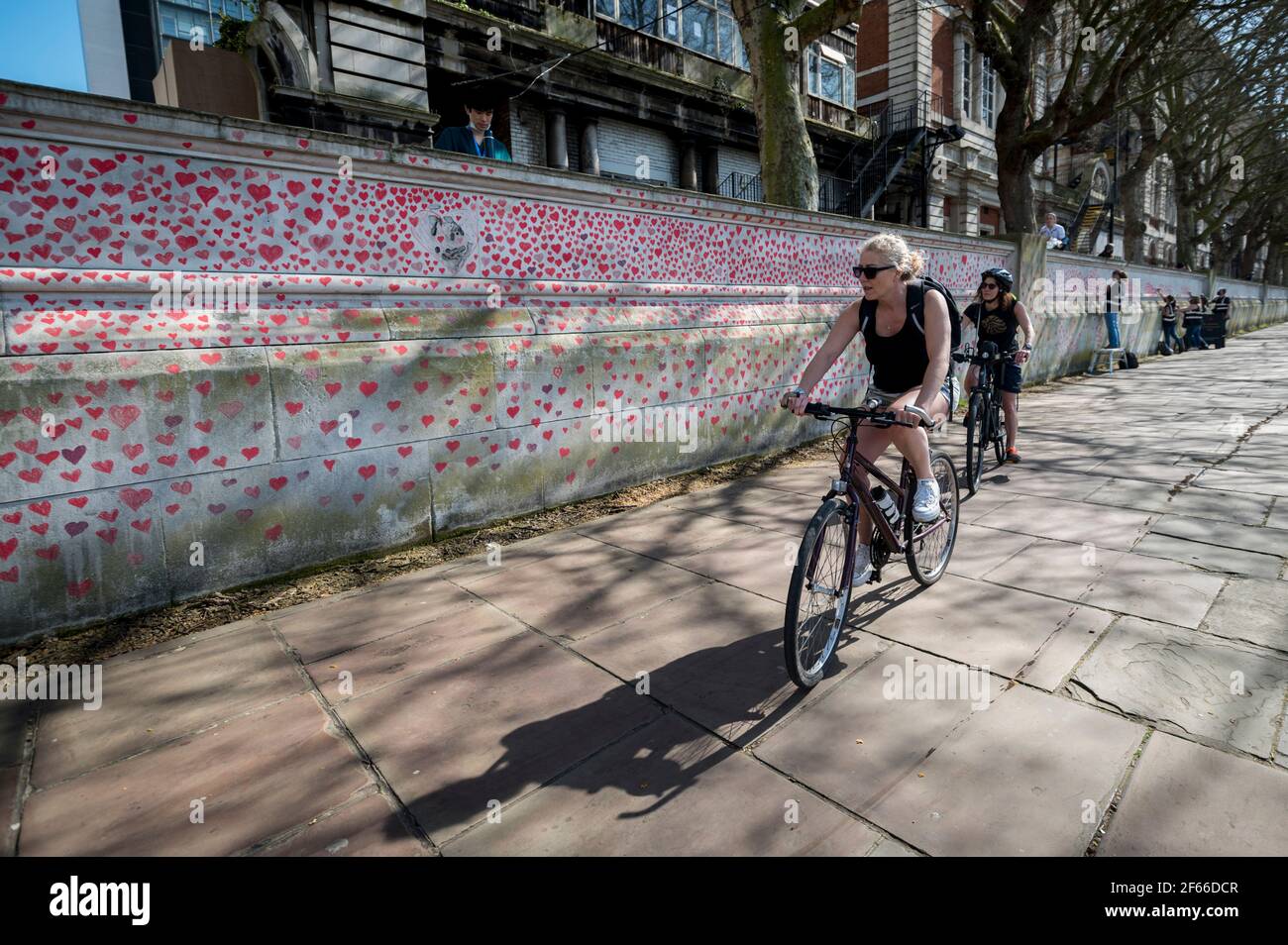 Londres, Royaume-Uni. 30 mars 2021. Les cyclistes passent les coeurs sur un mur à Lambeth, près de la Tamise, chaque coeur représentant quelqu'un qui est décédé pendant la pandémie de coronavirus au Royaume-Uni. Appelé le mur commémoratif national Covid, il a été créé par les familles bereaved Covid-19 pour la justice et s'étendra sur un demi-mile au moment où il sera terminé. Crédit : Stephen Chung/Alay Live News Banque D'Images