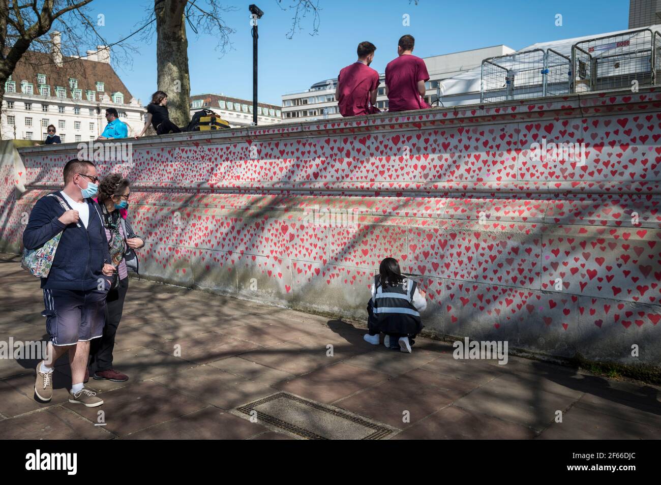 Londres, Royaume-Uni. 30 mars 2021. Les travailleurs du NHS au-dessus d'un volontaire dessinant le cœur sur un mur à Lambeth près de la Tamise, chaque cœur représentant quelqu'un qui est décédé pendant la pandémie de coronavirus au Royaume-Uni. Appelé le mur commémoratif national Covid, il a été créé par les familles bereaved Covid-19 pour la justice et s'étendra sur un demi-mile au moment où il sera terminé. Crédit : Stephen Chung/Alay Live News Banque D'Images