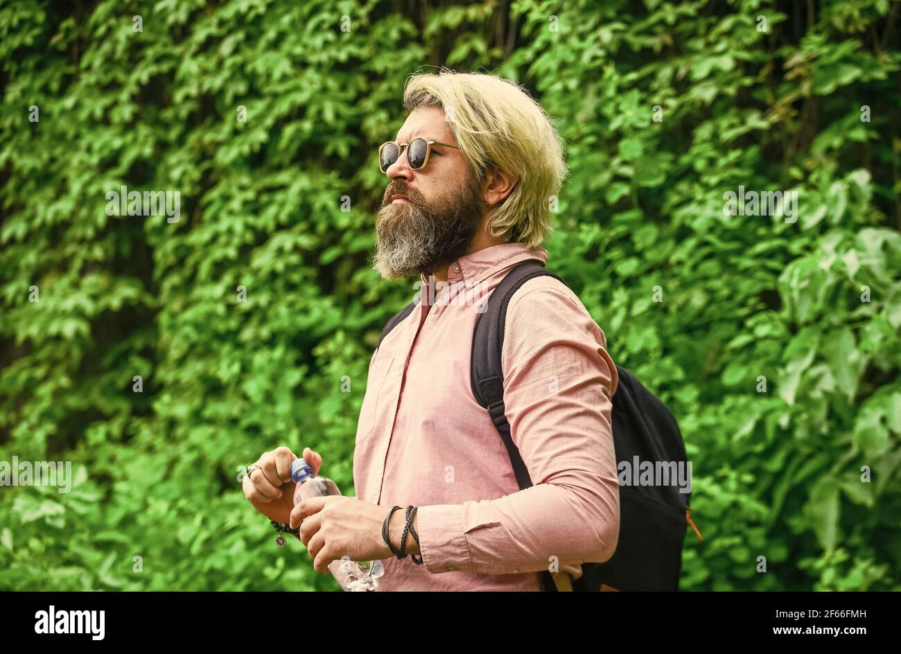 Un mode de vie sain. Chaleur estivale. Boire de l'eau claire. Sécurité et santé. Équilibre de l'eau. Homme barbu touriste eau bouteille plastique nature Banque D'Images