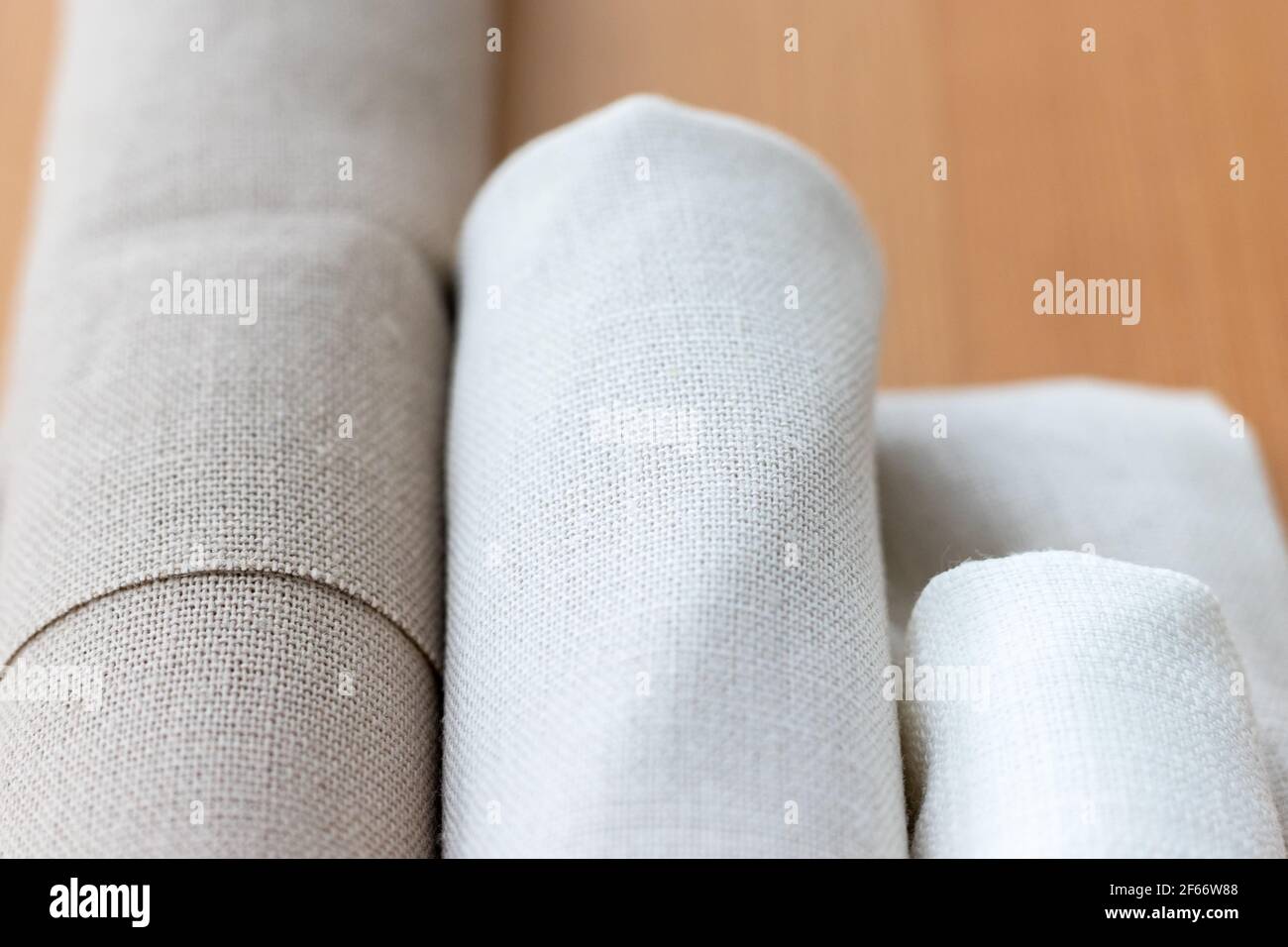 Trois rouleaux de linge naturel de différentes couleurs sur une table en bois. Mise au point sélective. Vue en gros plan. Arrière-plan flou Banque D'Images