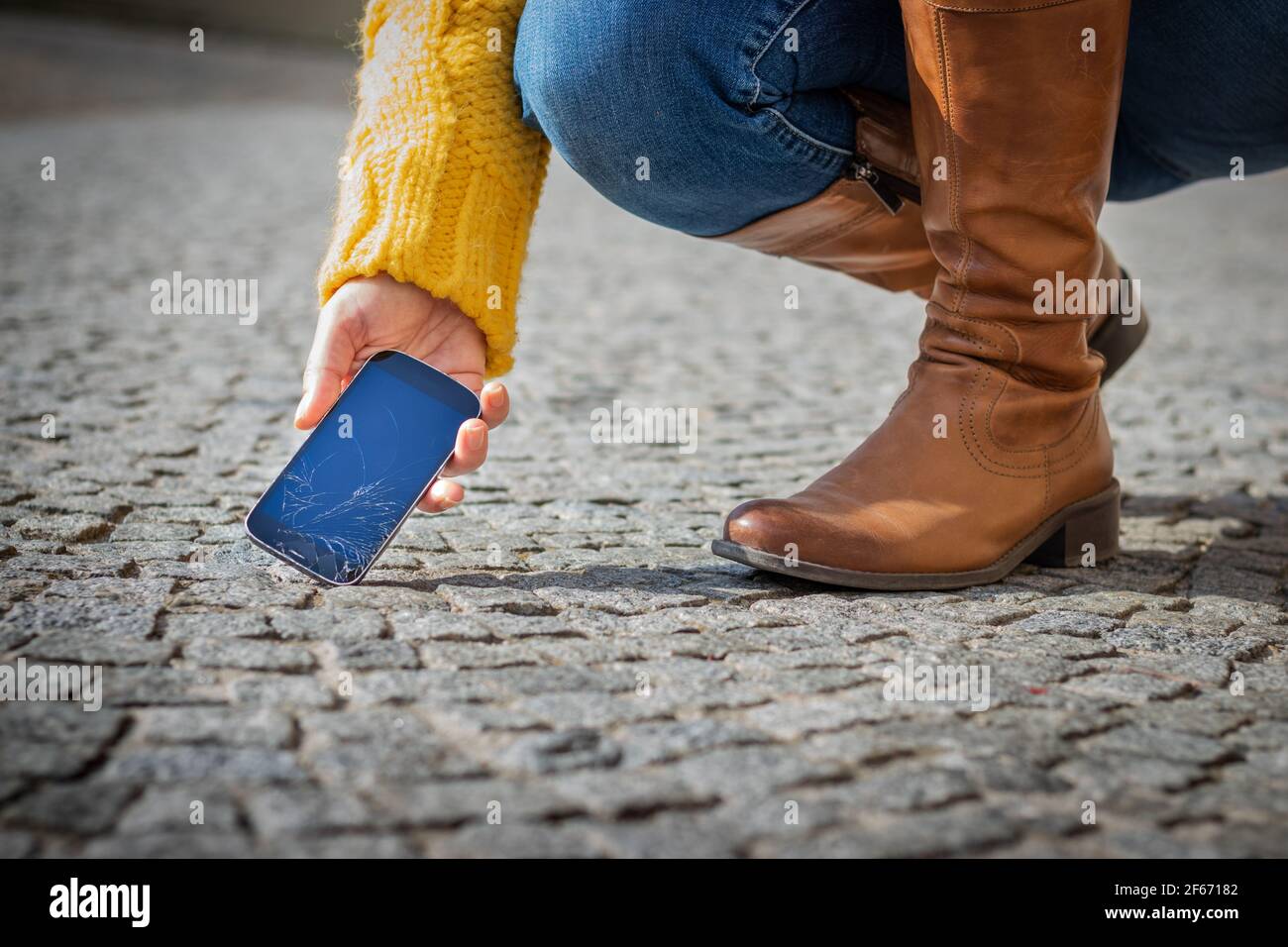 Femme prenant un smartphone cassé de la rue. Écran tactile fissuré sur le téléphone portable. Téléphone cellulaire endommagé Banque D'Images