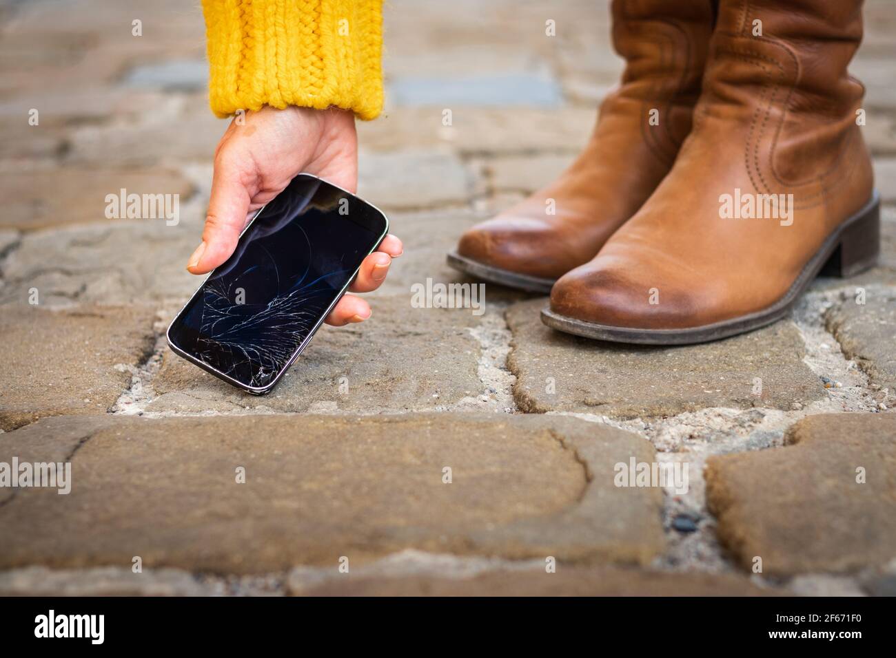 Une femme prend son téléphone intelligent cassé sur le trottoir. Écran tactile fissuré sur le téléphone portable. Téléphone cellulaire endommagé Banque D'Images