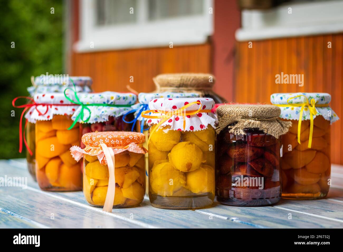 Compotes de fruits faits maison sur une table dans le jardin, concentration sélective. Aliments conservés en pots. Prune, pêche, abricot, compotes cerise Banque D'Images