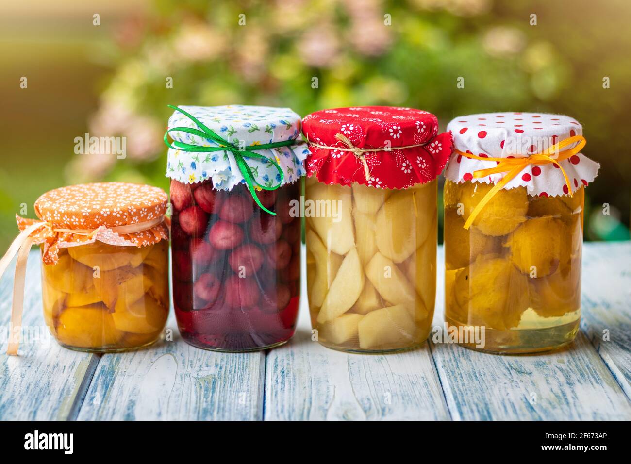 Compote de fruits en pot. Jardin comme arrière-plan. Mise au point sélective. Plats maison conservés sur table à l'extérieur. Banque D'Images