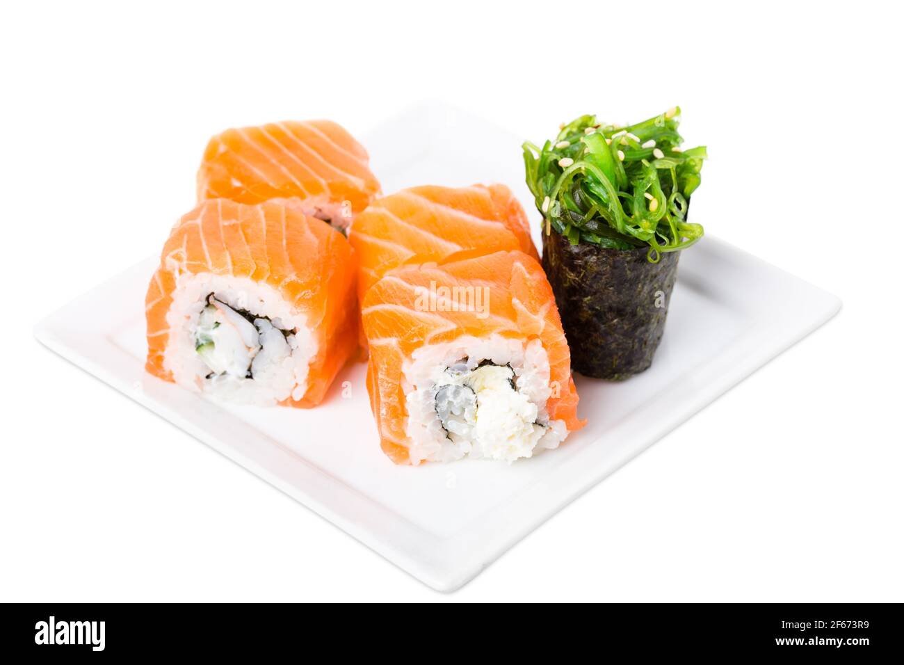 Roulé à sushis au saumon avec crabe des neiges et concombre. Servi avec du gunkan aux algues. Macro. La photo peut être utilisée comme arrière-plan entier. Banque D'Images