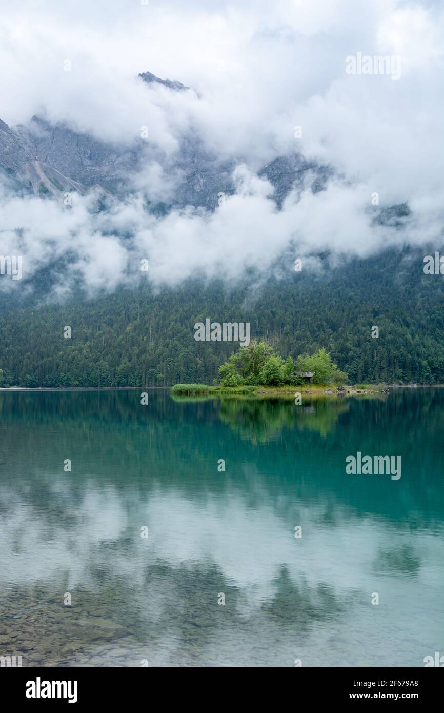 Petite île au milieu du lac Eibsee à un Journée nuageux avec montagne Zugspitze en arrière-plan Banque D'Images