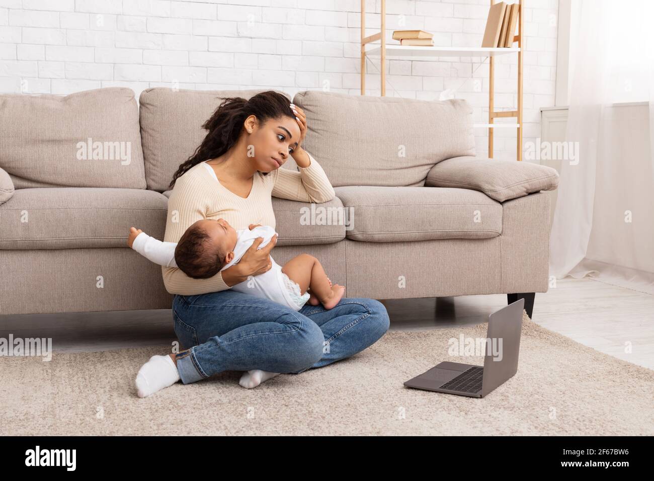 Mère noire épuisée tenant bébé pleure assis à l'intérieur de l'ordinateur portable Banque D'Images