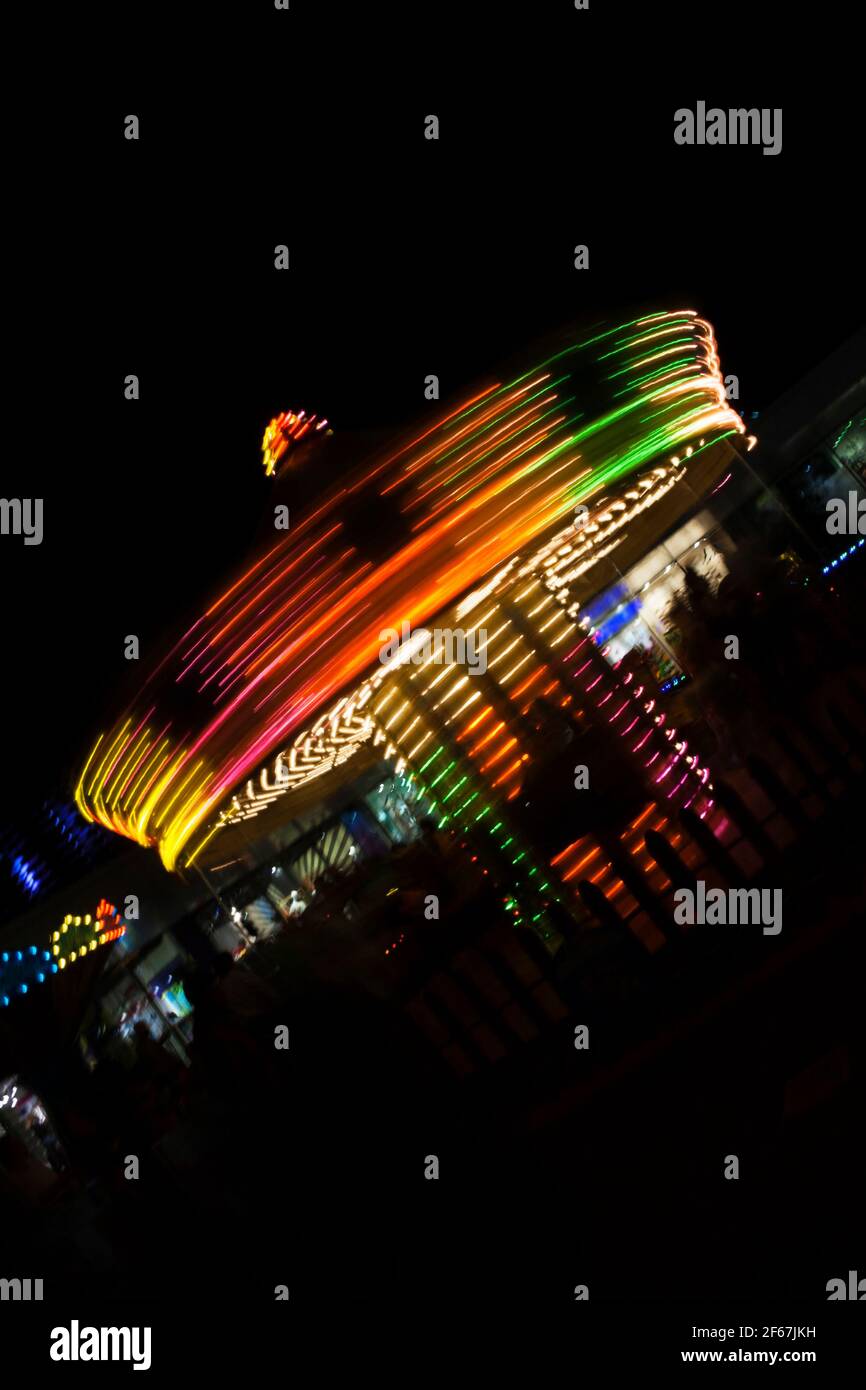 Look abstrait et coloré d'un carrousel tournant la nuit. Carrousel exposé long. Banque D'Images