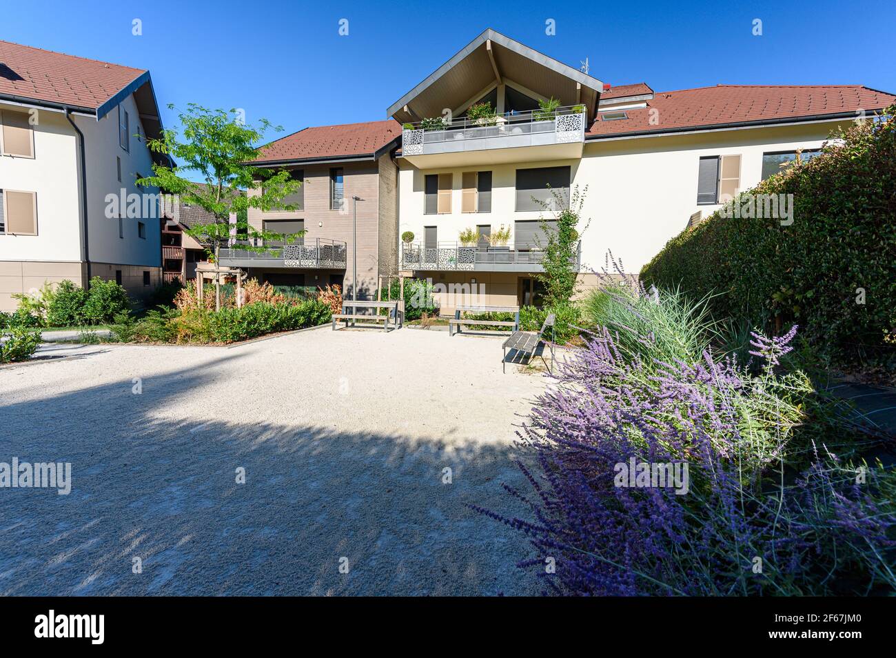 Lit de fleurs dans une zone de détente avec bancs en face de la maison. Vue sur l'immobilier résidentiel à Annecy, France Banque D'Images