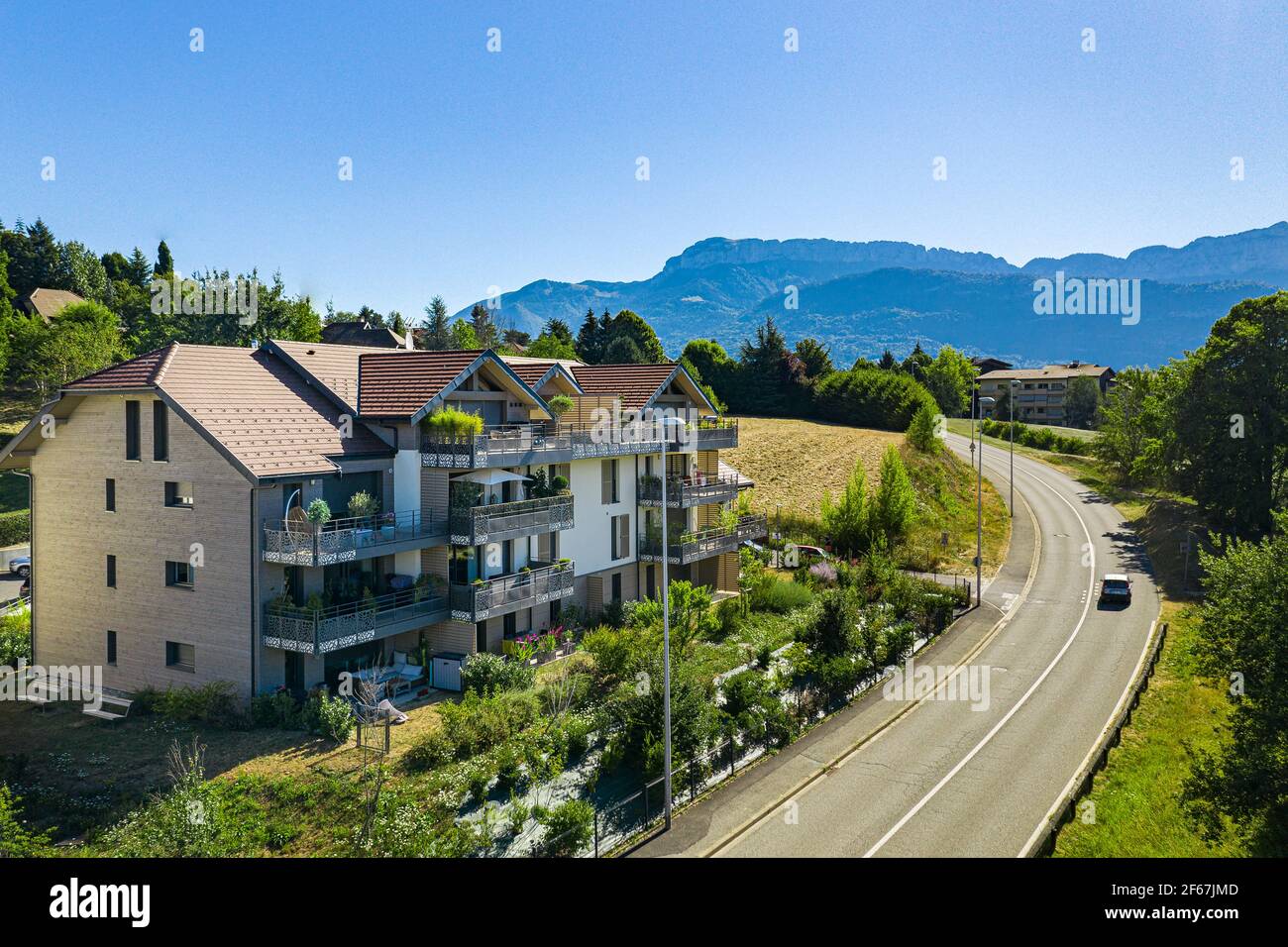 Route menant autour d'un bâtiment à plusieurs étages avec balcon. Vue aérienne de l'immobilier résidentiel à Annecy, France Banque D'Images