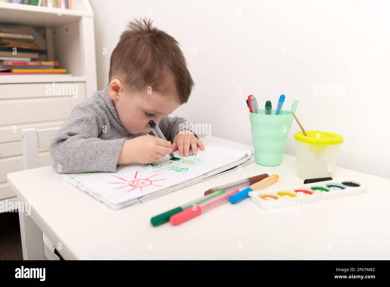Un petit garçon qui dessine dans sa chambre Banque D'Images
