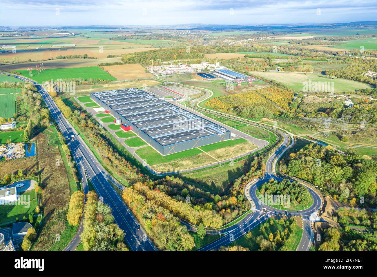 Prise de vue aérienne matinale de l'aréal logistique sur l'autoroute, dans un paysage plat. Transport et logistique, bâtiment industriel moderne et technologie. Banque D'Images