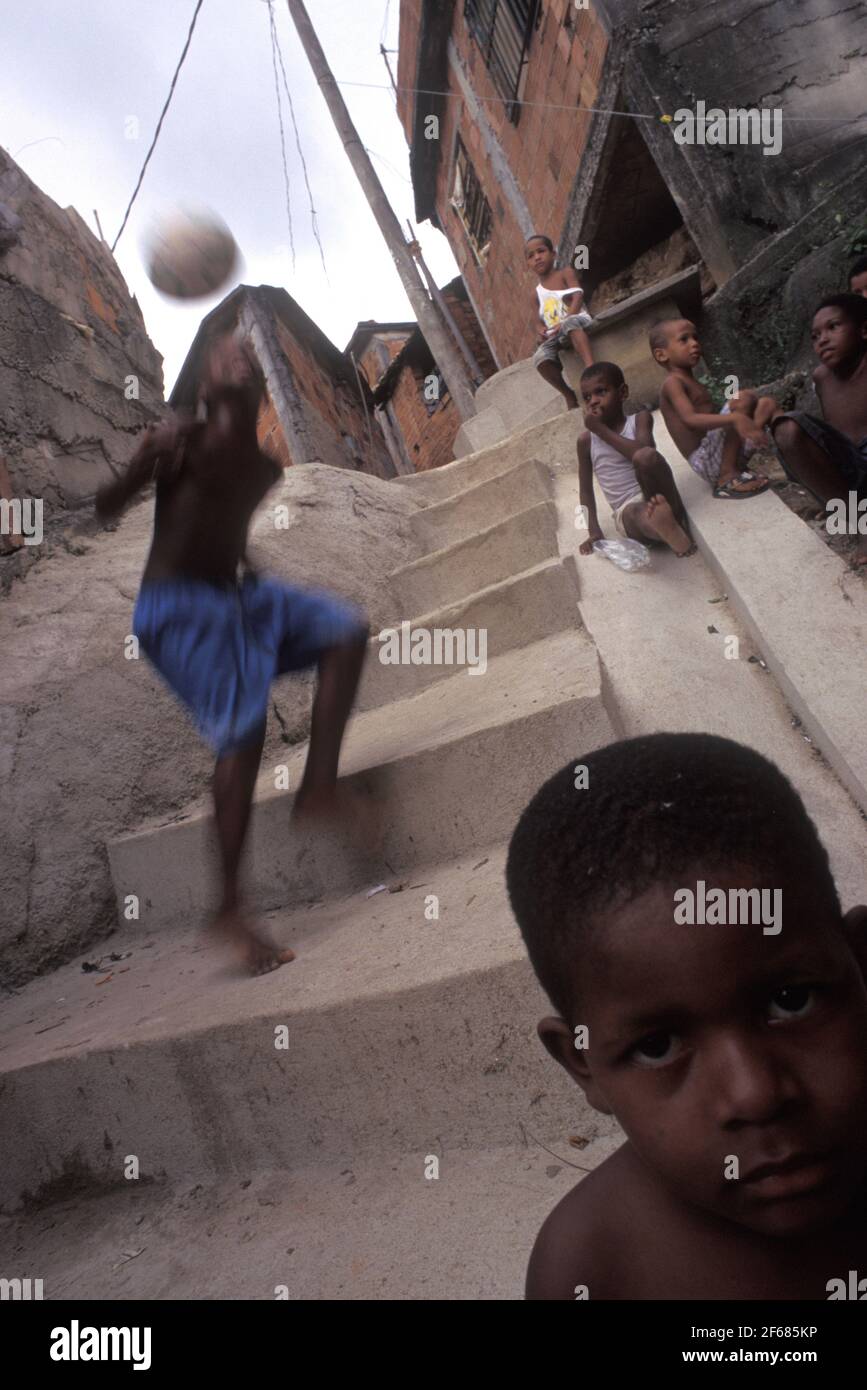 La vie quotidienne à Rio de Janeiro favela, les garçons noirs s'amusent avec le ballon de football - Morro da Mangueira. Banque D'Images