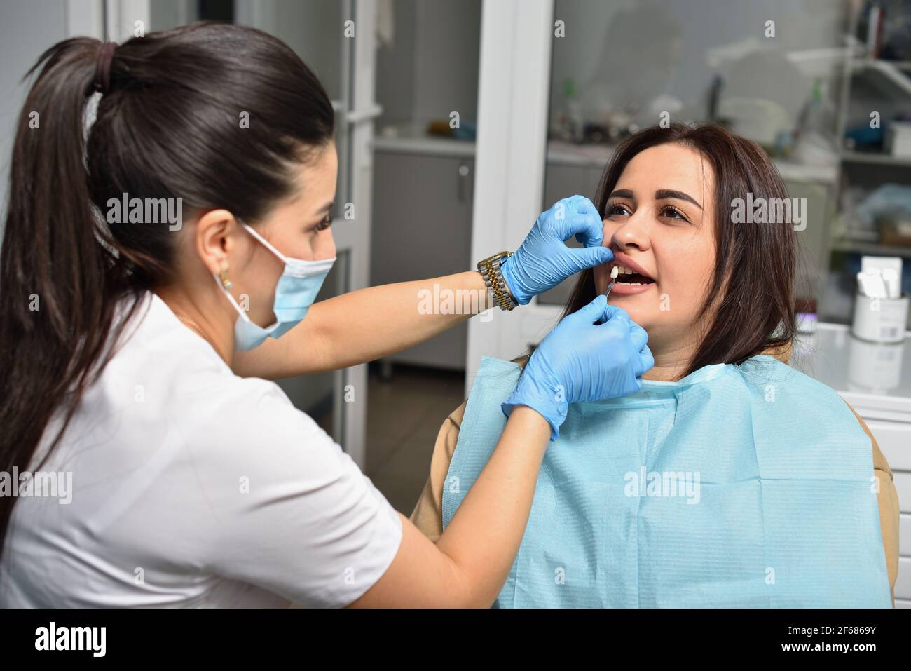 Le dentiste vérifie la correspondance des couleurs de l'émail du dents après l'installation de l'implant Banque D'Images