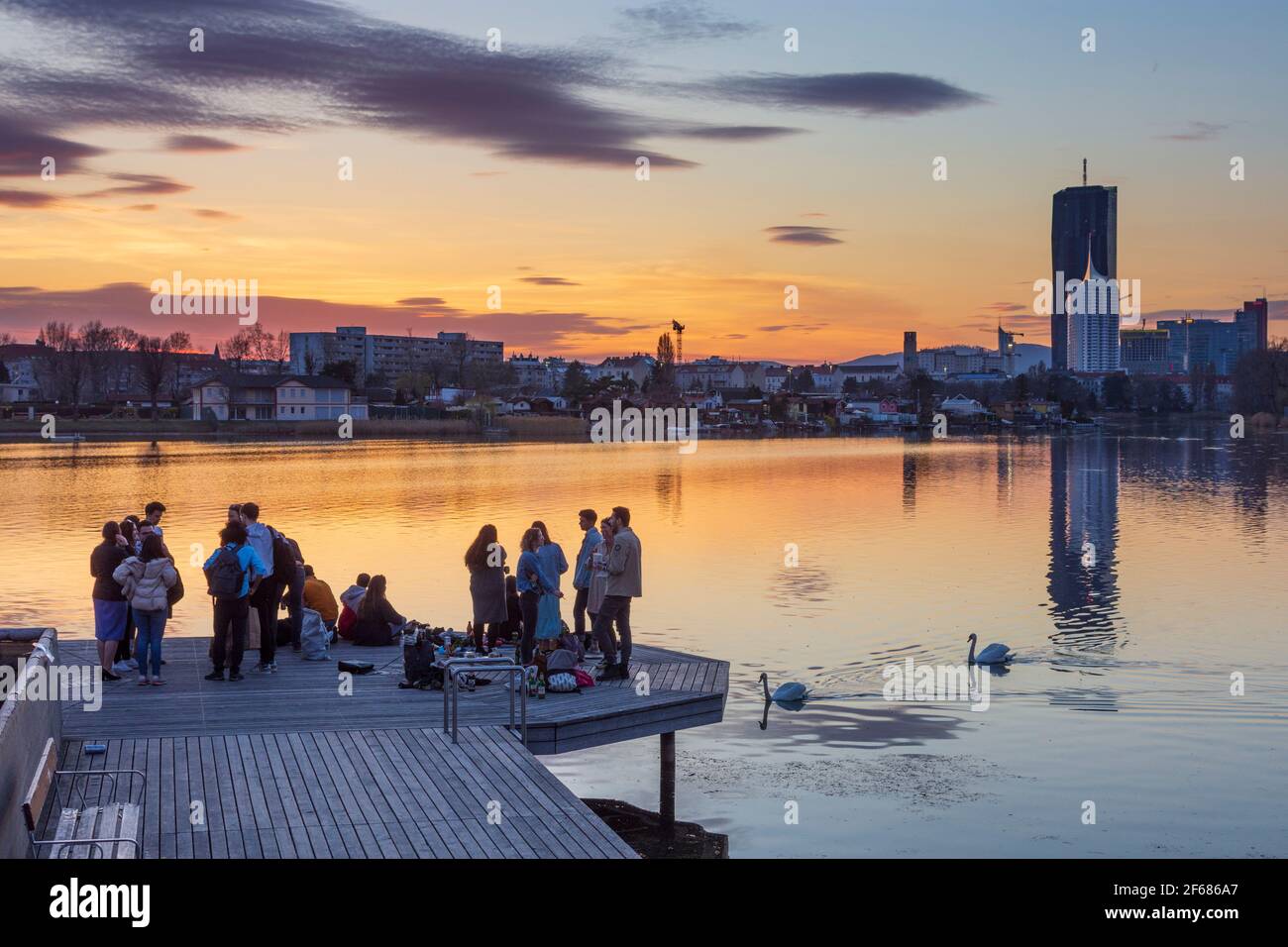 Wien, Vienne: Jeunes sur une plate-forme lors d'une fête au-dessus du lac de l'arbalète Alte Donau (vieux Danube) au coucher du soleil, bâtiments de Donaucity, DC Tour 1, Coro Banque D'Images