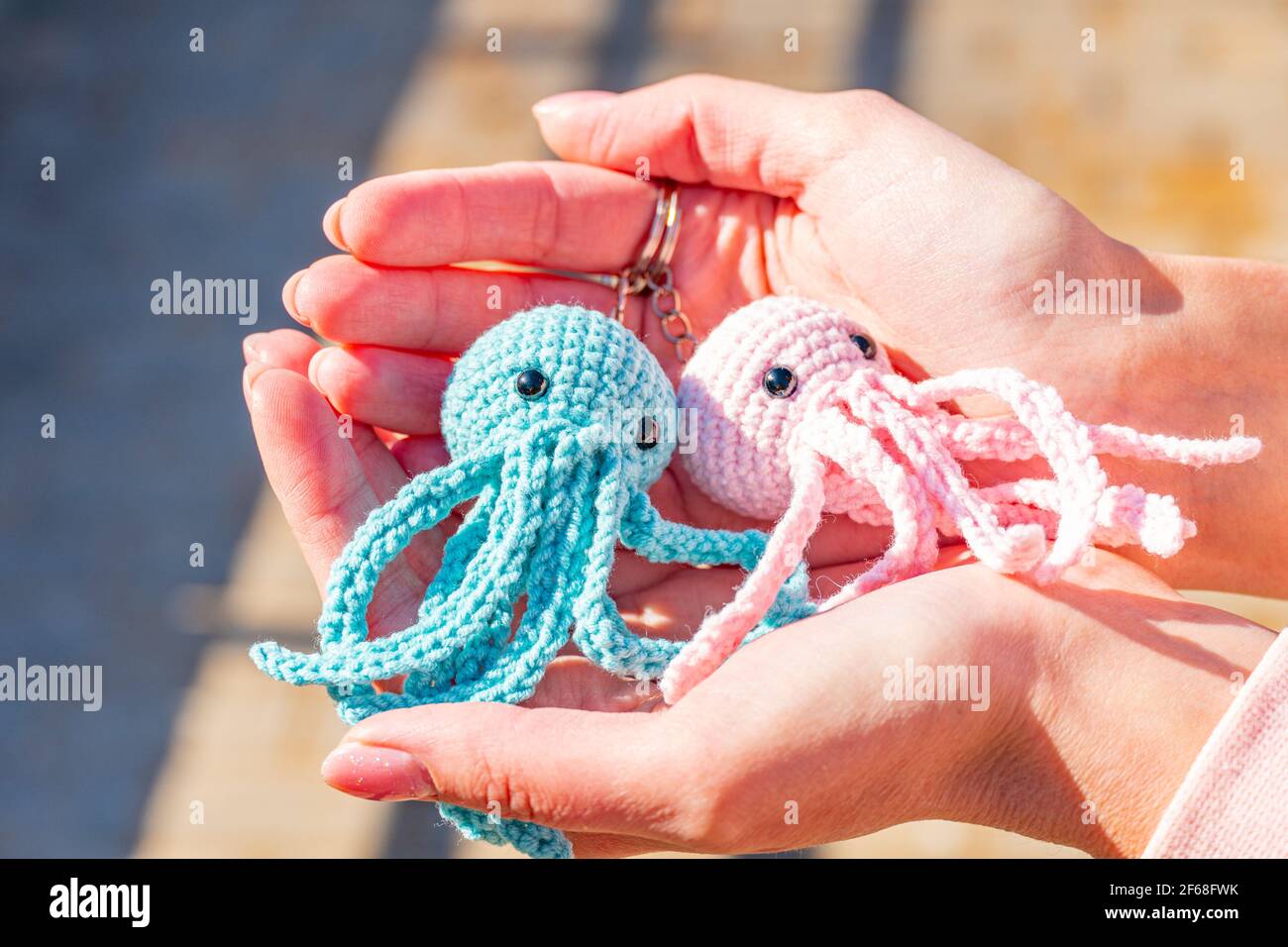 Porte-clés en tricot poulpe bleu et rose sur une main femelle gros-plan,  porte-clés tricotés en peluche Photo Stock - Alamy