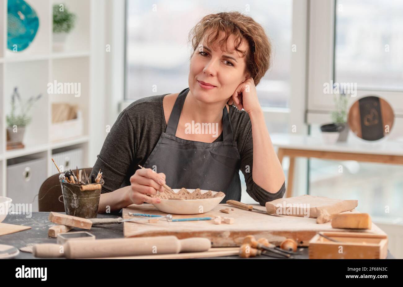 Femme assise à table avec poterie Banque D'Images