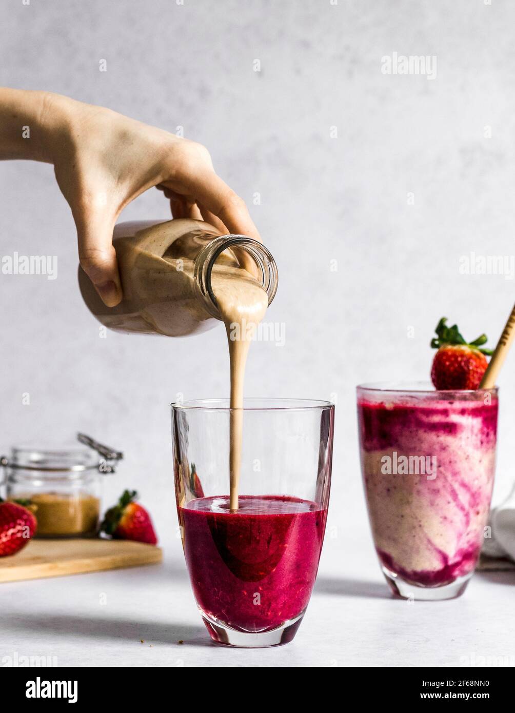 Vegan, doux, sain beurre d'arachide et gelée smoothie étant versé dans un verre, un autre smoothie est déjà fait et prêt à être bu. Banque D'Images