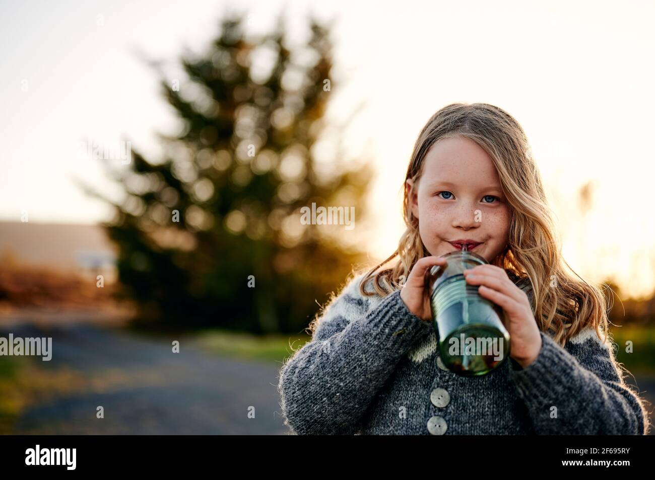 Une fille qui apprécie une boisson fraîche au coucher du soleil Banque D'Images