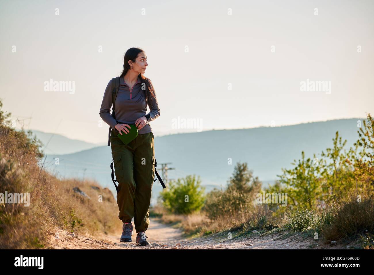 Une femme exploratrice marche le long d'une route de terre observant la nature Banque D'Images