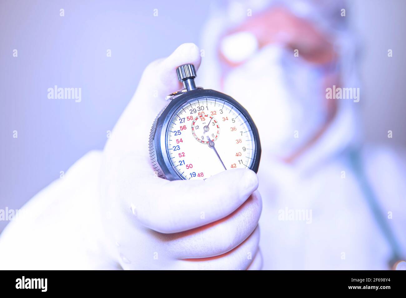 Un médecin portant un masque chirurgical et des gants chirurgicaux tenant un chronomètre pour une action rapide afin de résister à la propagation du covid 19 et à la vaccination. Sur fond blanc Banque D'Images
