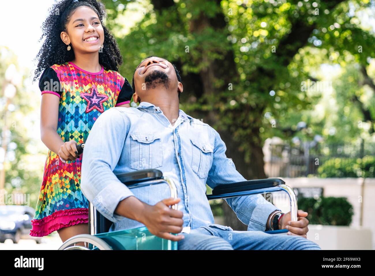 Homme en fauteuil roulant en train de marcher avec sa fille. Banque D'Images
