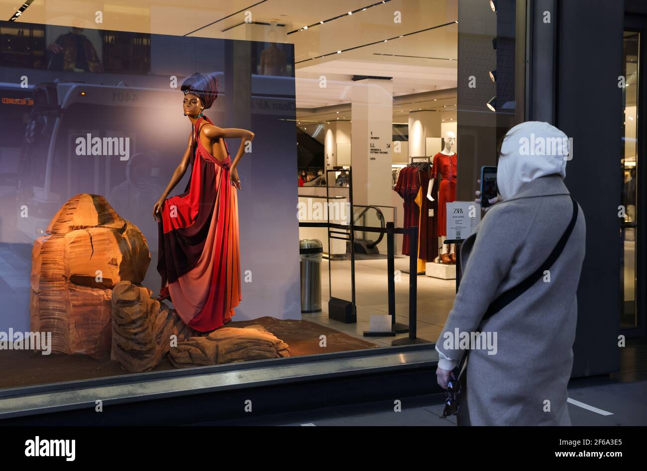 Un homme prend une pause pour photographier une vitrine Zara, dans le  quartier de Manhattan à