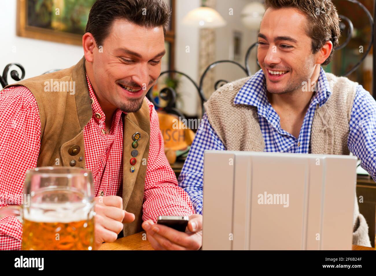 Deux amis en pub bavarois en vêtements traditionnels assis sur une table dans un pub avec coffre Banque D'Images