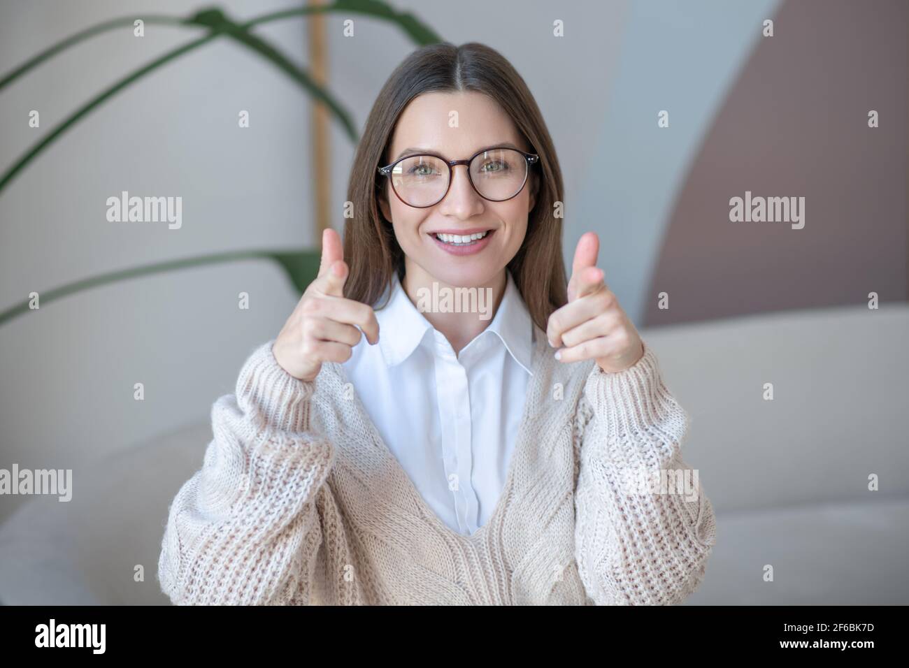 Femme à cheveux longs en lunettes souriant joliment et regardant content Banque D'Images