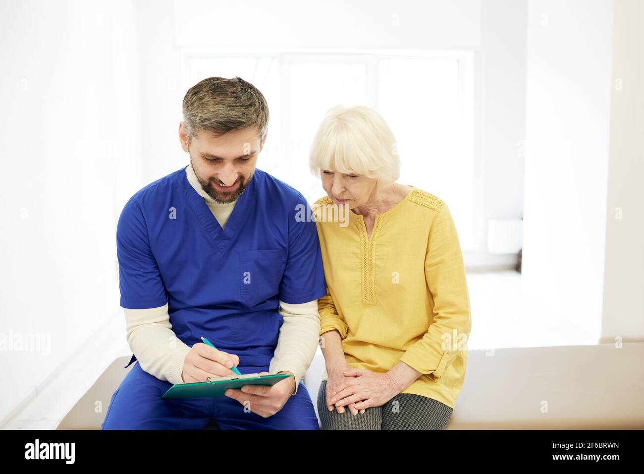 Patiente sénior lors d'une consultation avec son physiothérapeute masculin dans un centre de remise en forme Banque D'Images