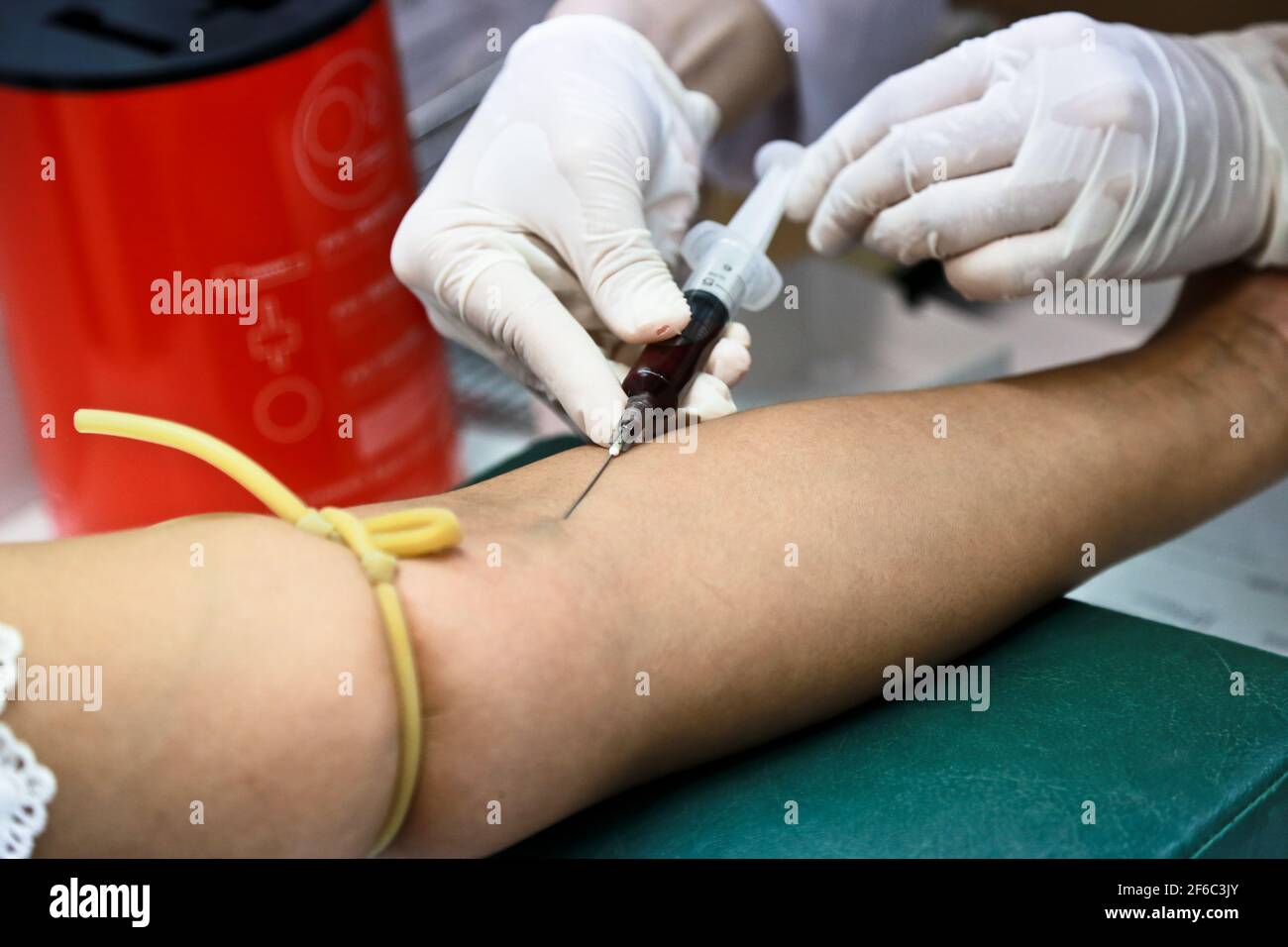 Le médecin ou l'infirmière porte des gants médicaux blancs en utilisant une seringue à aiguille pour prélever un échantillon de sang du bras du patient à l'hôpital. Banque D'Images