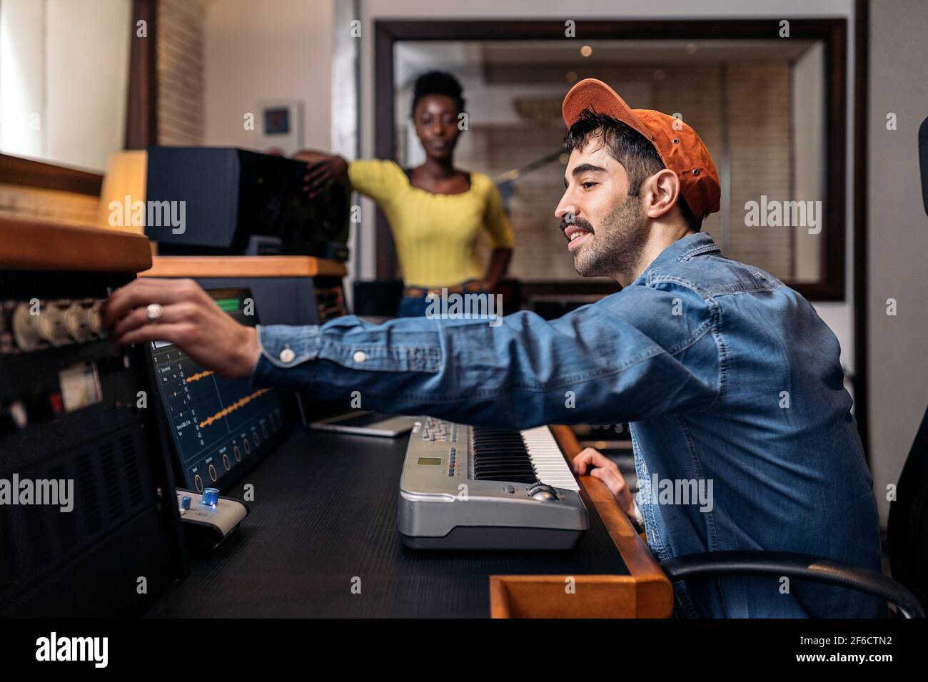 Photo de la bonne femme noire en studio de musique et producteur de sexe masculin utilisant un clavier de piano électronique. Banque D'Images