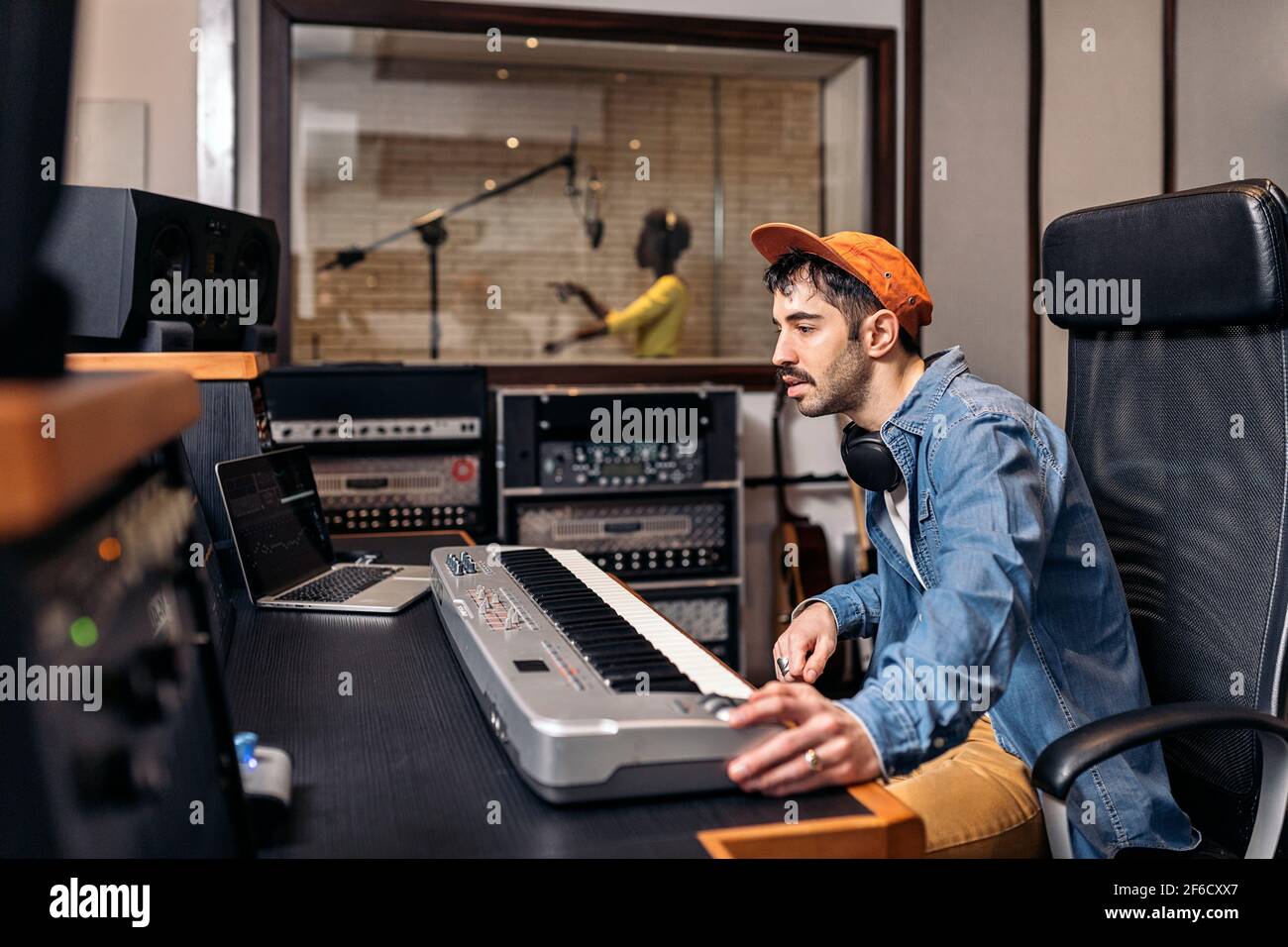 Photo d'un producteur de musique masculin travaillant avec un chanteur noir dans un studio de musique cool. Banque D'Images