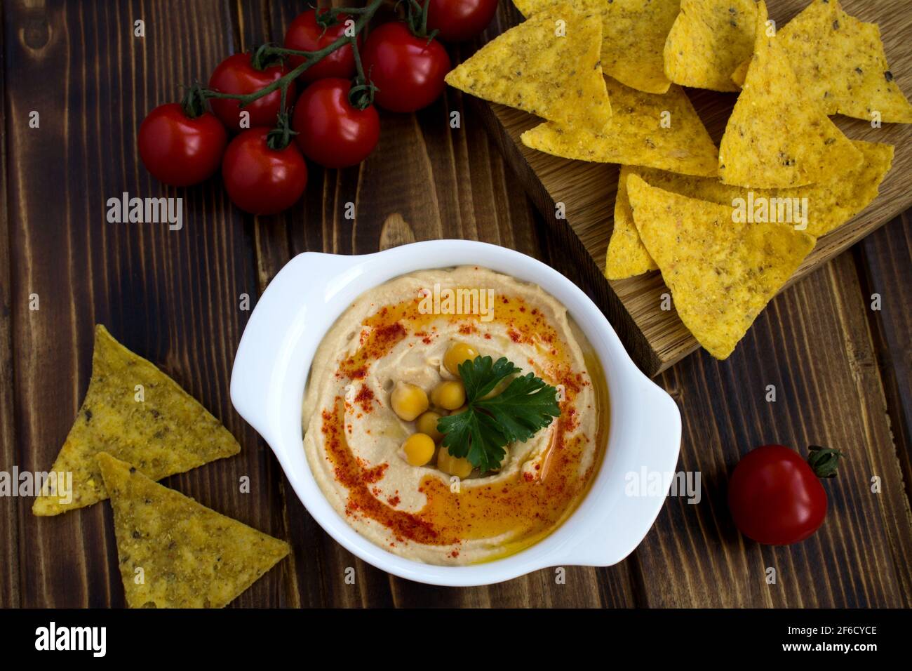 Houmous dans la plaque blanche, cerise et copeaux sur le fond en bois.vue du dessus. Banque D'Images