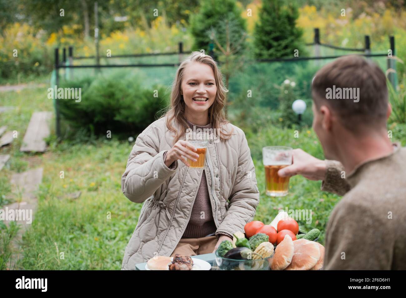 Un couple marié célèbre l'achat de biens immobiliers, dans le pays. Une fille et un gars s'assoient à une table de pique-nique et claque des tasses à bière. Banque D'Images