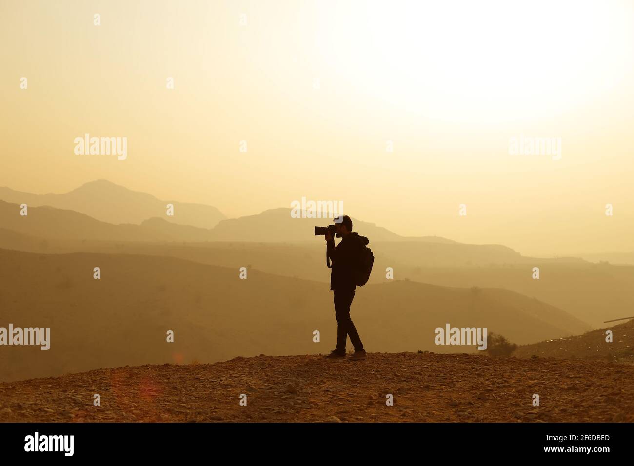 Photographe de la nature en action. Silhouette d'homme au-dessus d'un nuage brumeux, paysage de vallée du matin. Banque D'Images