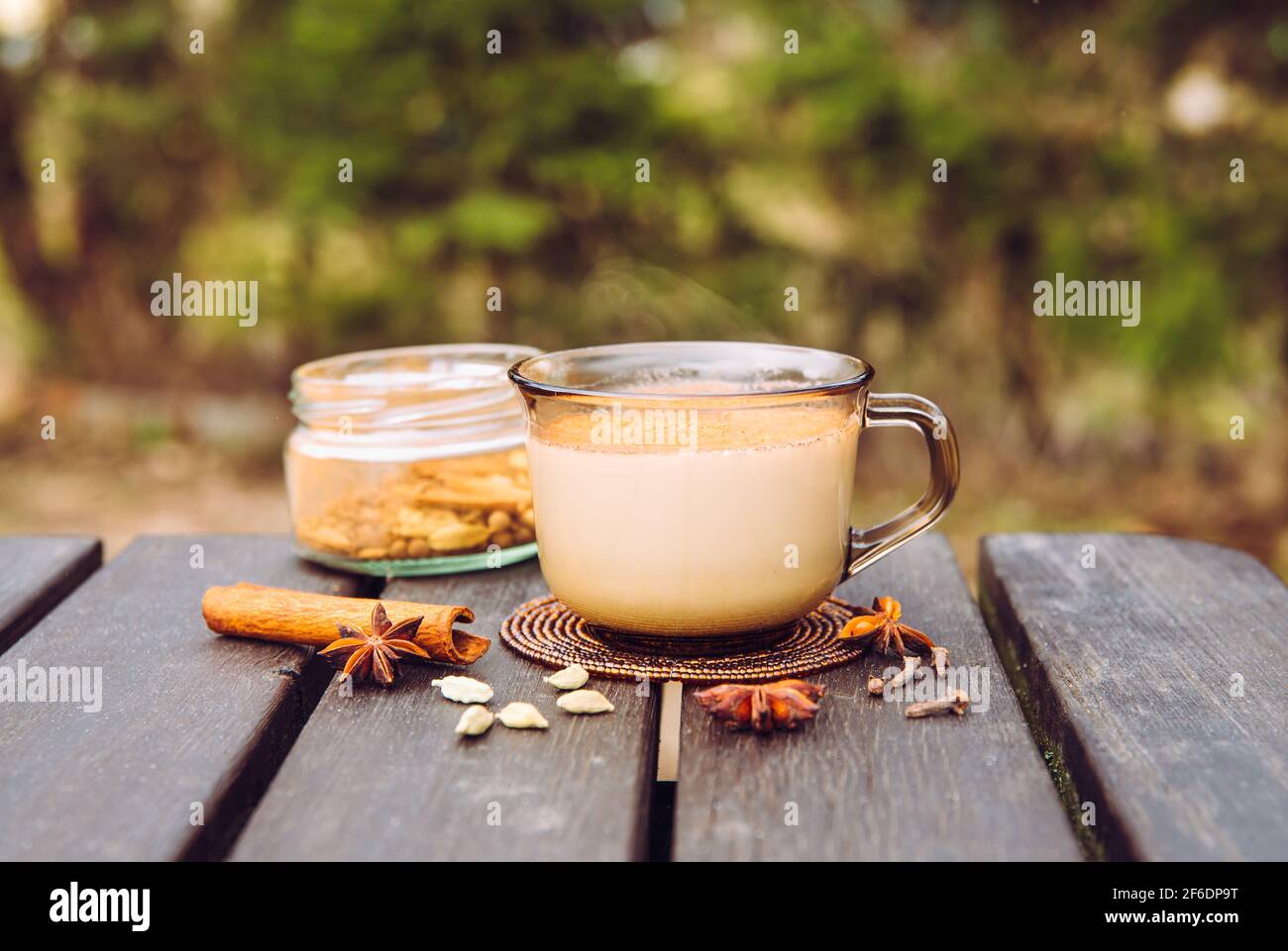 Boire Chai latte au pique-nique en plein air concept. Tasse de chai latte chaud sur table de pique-nique au camping, pot avec mélange d'épices sur fond. Banque D'Images