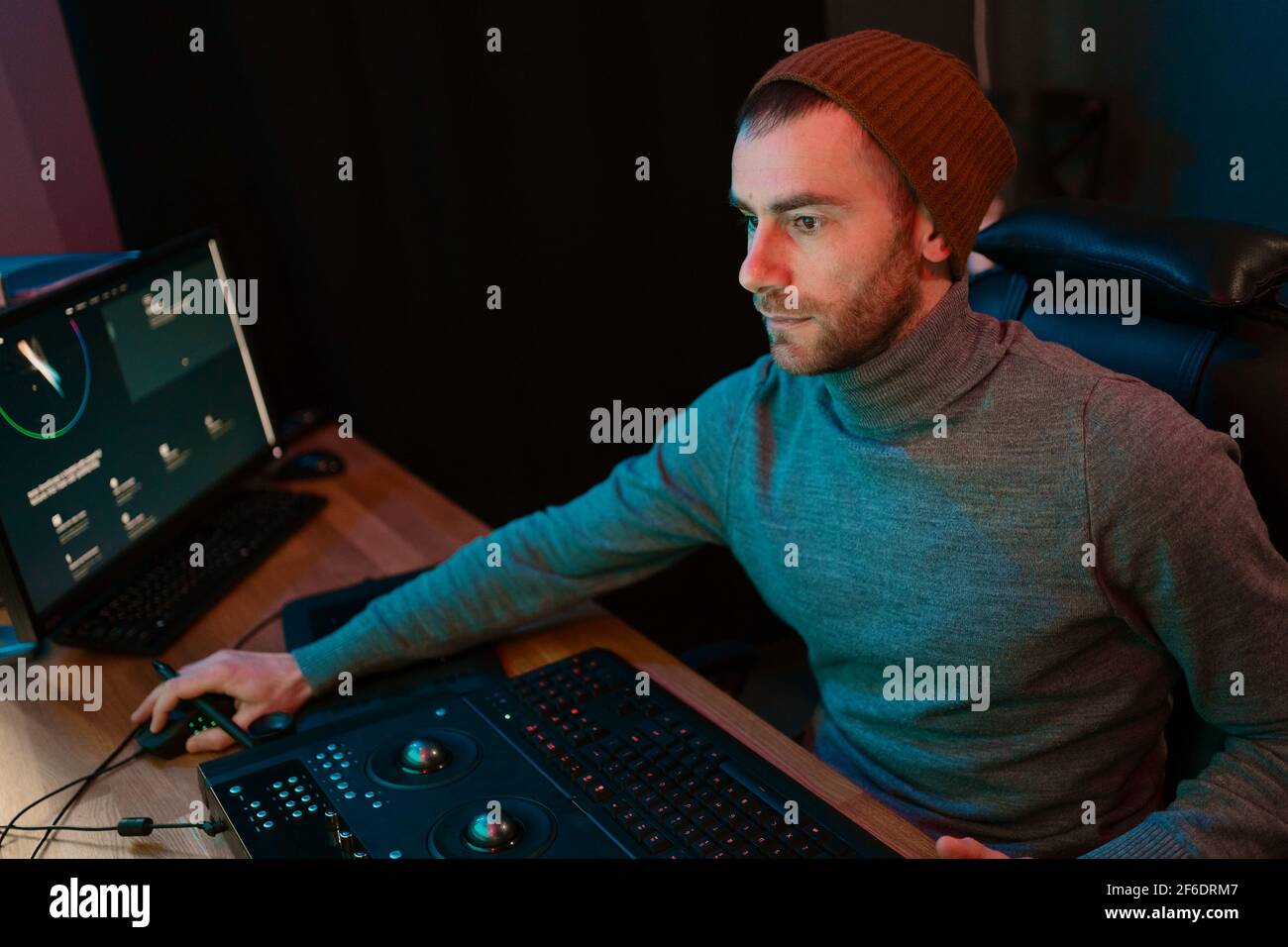 Attrayant Homme Video Editor travaille avec des films ou vidéo sur son ordinateur personnel, il travaille dans Creative Office Studio ou à la maison. Lampes au néon Banque D'Images