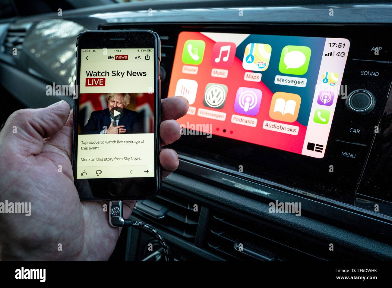 Un homme utilisant son Apple iphone se connecte aussi à l'unité de divertissement et de communication dans un VW Polo. Banque D'Images