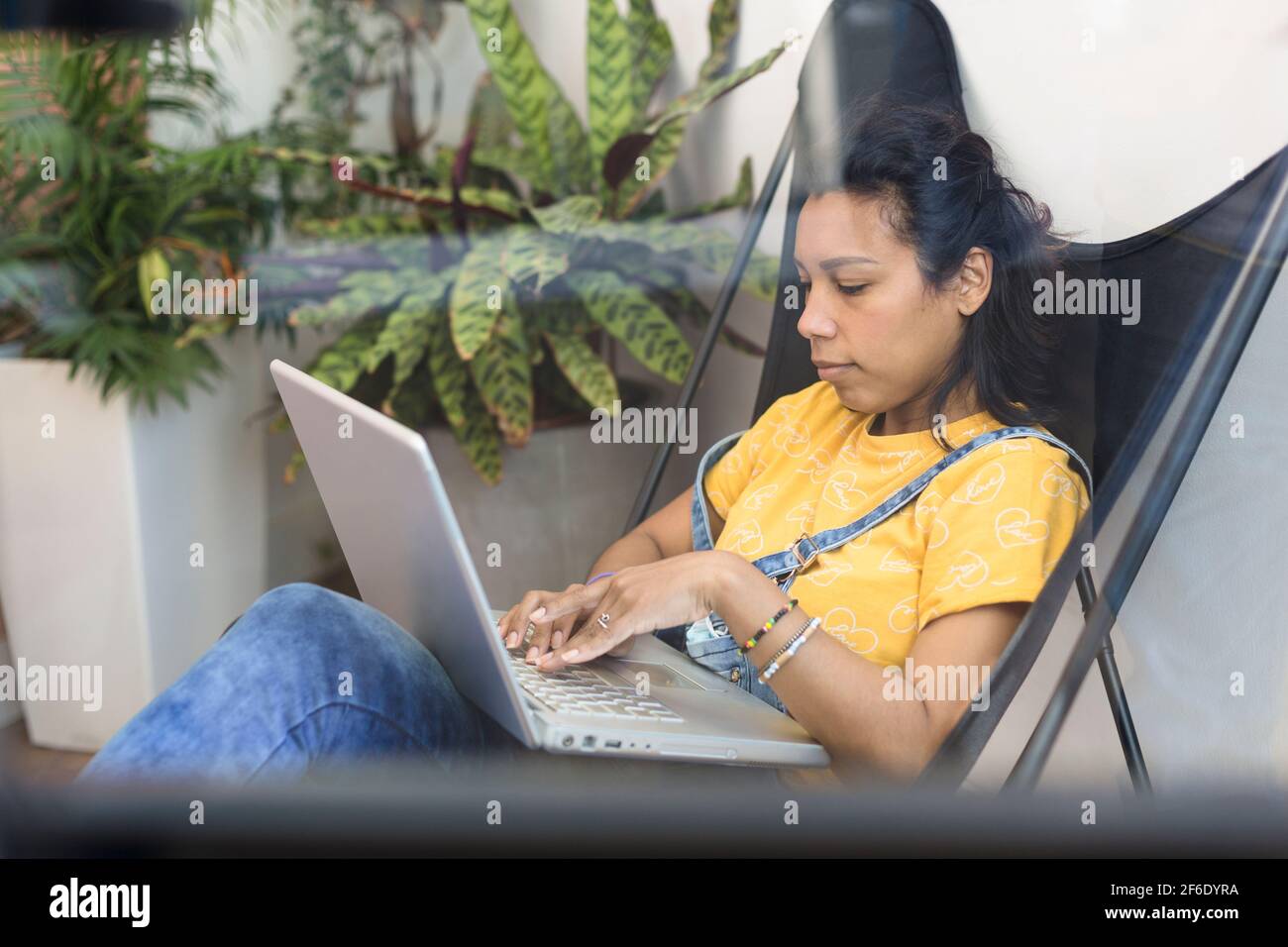 Vue franche d'une jeune femme hispanique travaillant avec son ordinateur portable de chez elle. Espace pour le texte. Banque D'Images
