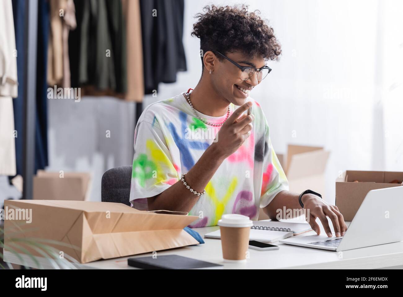 Souriant propriétaire de petite entreprise afro-américaine utilisant un ordinateur portable près de plats à emporter boissons et forfaits Banque D'Images