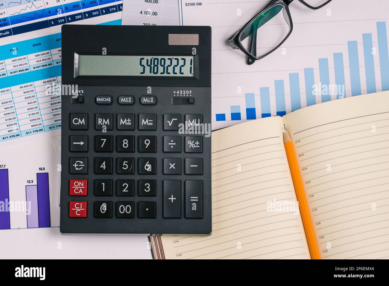 Calculatrice, ordinateur portable ouvert et tableau financier. Tableau avec nombres et données analytiques. Prévision de la hausse ou de la baisse des actions. Analyse des ventes figur Banque D'Images