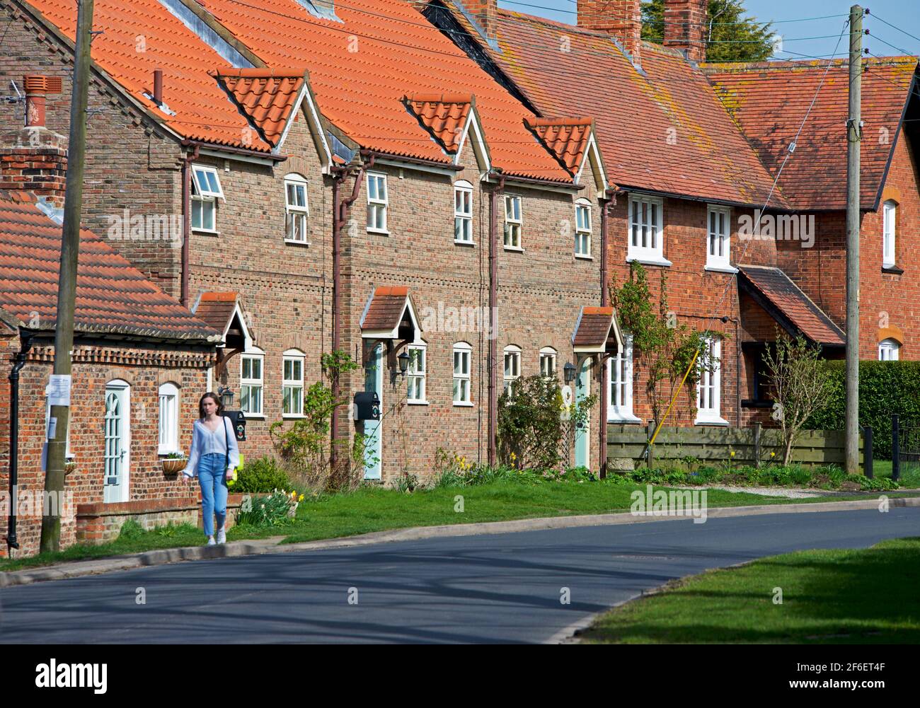 Jeune femme marchant dans le village de Wheldrake, North Yorkshire, Angleterre Banque D'Images